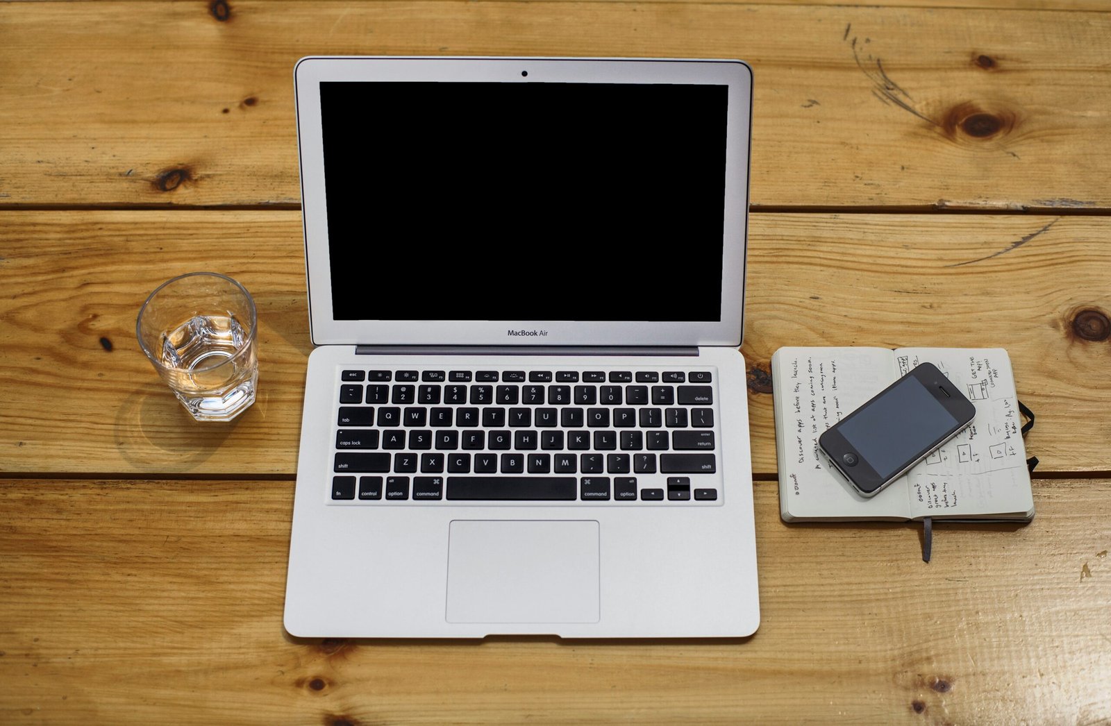 MacBook Air beside black iPhone 4 and drinking glass